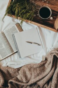 An open notebook and pen on a kitchen table next to a steaming mug, with soft morning light streaming in.