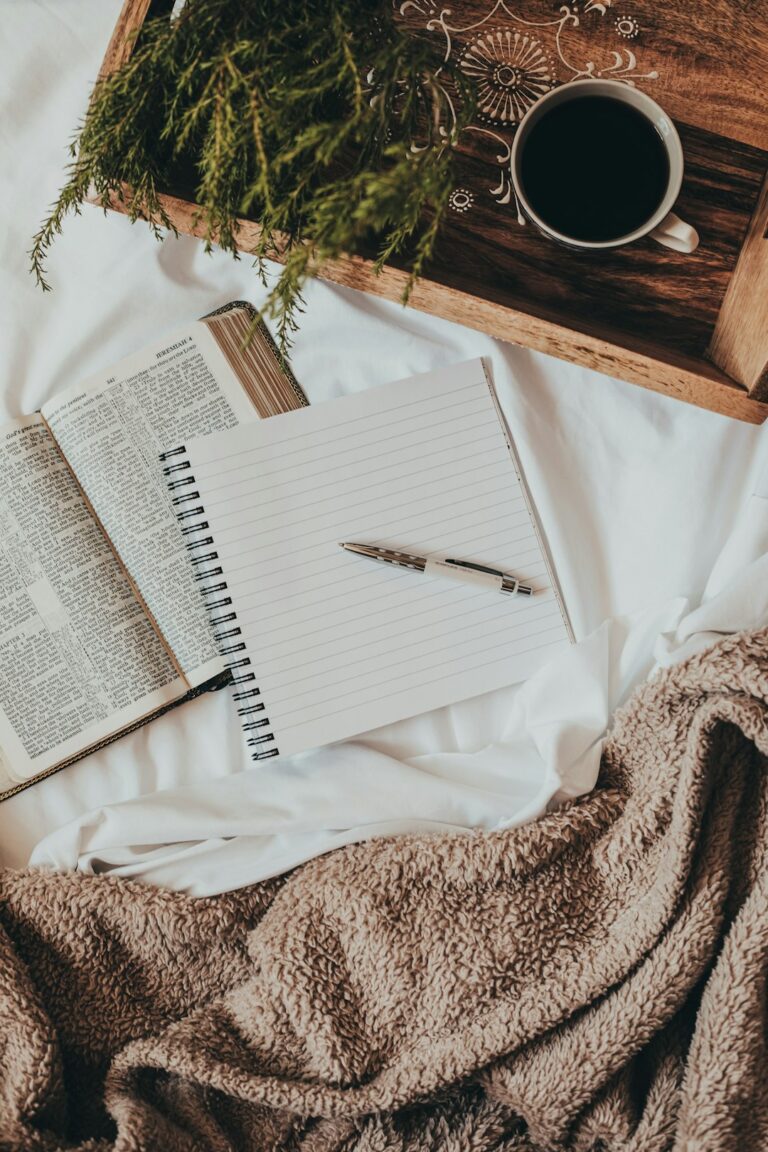 An open notebook and pen on a kitchen table next to a steaming mug, with soft morning light streaming in.