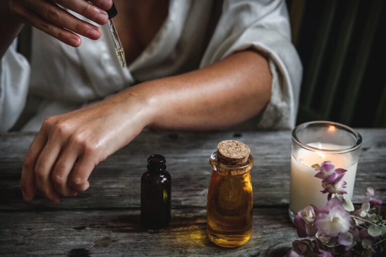 A person relaxing at home with an essential oil diffuser and a book on a wooden table.