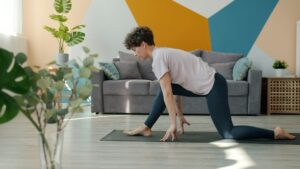 Person sitting near a window practicing calm breathing with one hand on the chest and one on the abdomen.