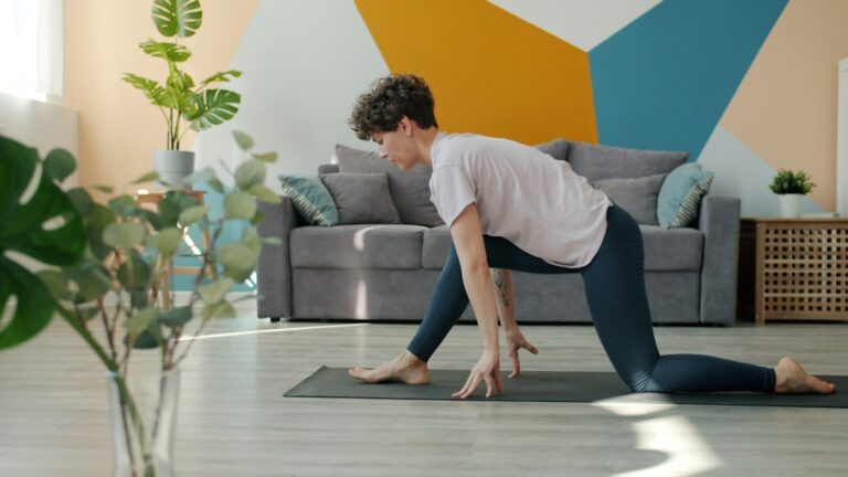 Person sitting near a window practicing calm breathing with one hand on the chest and one on the abdomen.