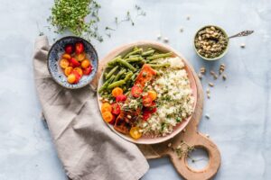 A home kitchen table with vegetables, beans, eggs, oats, walnuts, and salmon arranged for balanced meals.
